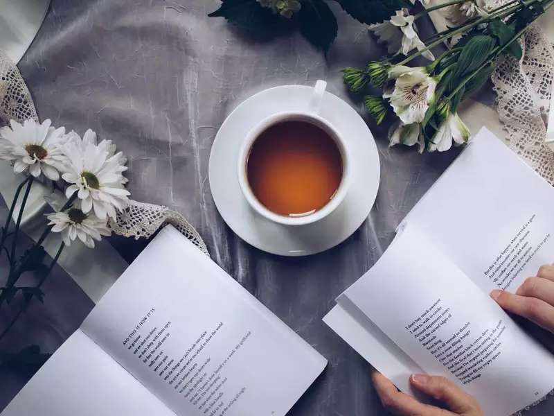 bird's eye view of a cup of coffee next to two open books of poetry